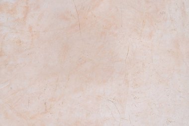 İnce çizikler ve kusurlarla bej kaplama bir duvar, kırsal ve doğal bir arka plan yüzeyi oluşturuyor..