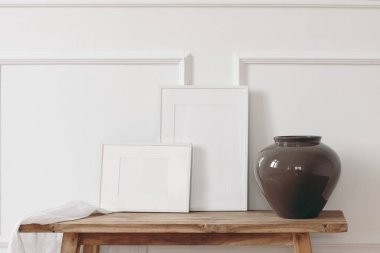 Şık bir ev, iç dekorasyon natürmort fotoğraf. Eski ahşap bankta kahverengi seramik vazo. Boş beyaz yatay ve dikey çerçeve modellemeleri. Duvar kalıbı arka plan, süsleme dekoru, boş kopya alanı