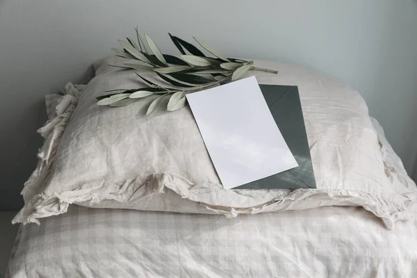 Fluffy beige linen, cotton gingham pillows. Green olive tree branches. Pile of checkered cushions. Greeting card, invitation mockup i sunlight. Blurred feminine still life background, sleeping concept