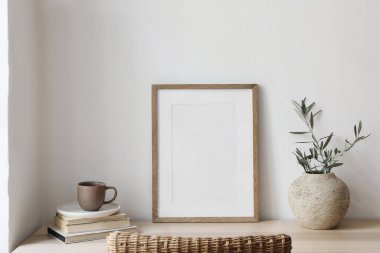 Resim çerçevesinin kapanışı, poster modeli. Ahşap masanın üzerinde zeytin dalları olan vazo. Bulanık rattan sandalye. Bir fincan kahve, kitaplar. Yaz sanatsal Akdeniz iç mimarisi, çalışma alanı, ev ofisi.
