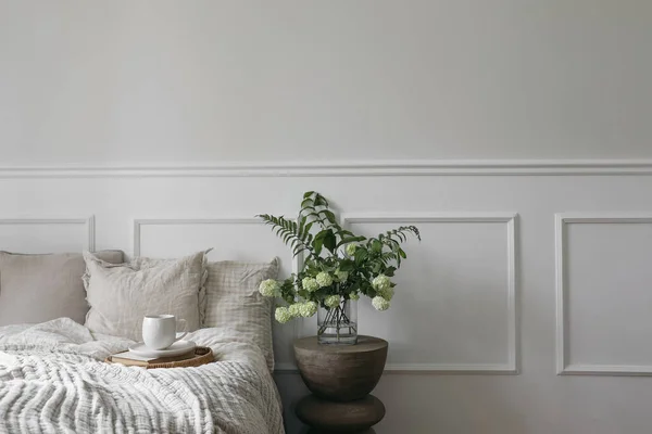ベッドで朝食 コーヒー ウィッカートレイのカップ 白いビブラム ソロモンのシール花の緑の花束 近代的なBoho夜のスタンド 寝室の眺め ベージュの枕 リネンの毛布 エレガントな成形 — ストック写真
