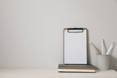 Tahta pano, defter ve kalem tutacağıyla ahşap bir masa. Merkez ofis, ofis malzemeleri ve bej duvar boşluğu olan yaratıcı masa, zarif iç mekan, ev dekorasyonu. Kimse..