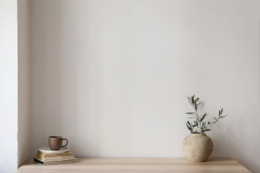 Zarif Akdeniz iç mimarisi. Zeytin dalı uzatılmış klasik vazo, bir fincan kahve. Tahta masadaki kitaplar. Oturma odası hala hayat dolu. Boş duvar kopyalama alanı, modern ev, daire tasarımı, insan yok.