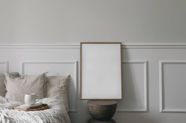 Zarif bir yatak odası iç mimarisi. Modern organik sehpada dikey ahşap çerçeve modeli. Tepside bir fincan kahve. Yatak konsepti kahvaltısı, bej keten fırlatma. Beyaz duvar arkaplanı.