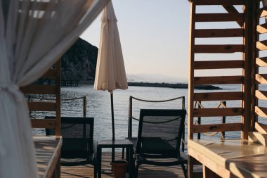 Zarif ahşap çardak. Beyaz tenteli, insansız bir plaj salonu. Sabah deniz manzarası. Şemsiye, güneşlik. Alanya bölgesinde Akdeniz 'in güzel bir plajında yer alan Konakli, Türkiye