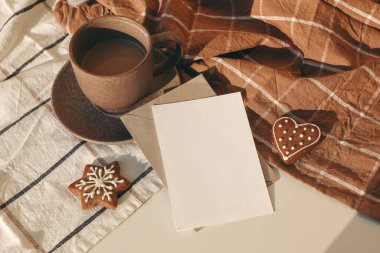 Kış şenliği natürmort. Bir fincan kahve, yıldız ve kalp şeklinde zencefilli kurabiye damalı masa örtüsü ve güneş ışığı. Noel kahvaltısı kavramı. Boş tebrik kartı, davetiye maketi, düz çizgi
