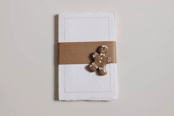 Blank notepad mockup. Cotton paper diary with rough edges, craft belly band, tape isolated on beige table background. Gingerbread man cookie Christmas still life, winter stationery flatlay, top view.