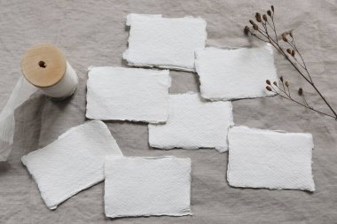 Kış düğün kırtasiyesi hala hayat konsepti. Boş pamuk işi seti, yer kartları ya da davetiye maketleri. Kuru çiçek, bej keten masa örtüsünde tohumlar. Düz, seyrek. Üst görünüm