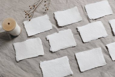 Pamuk işi kompozisyonu, yer kartları. Boş davetiyelerin maketleri satırda. Kış düğün kırtasiyesi hala hayat dolu. Kuru çiçek, bej keten masa örtüsünde tohumlar arka plan, düz yatış, üst manzara.