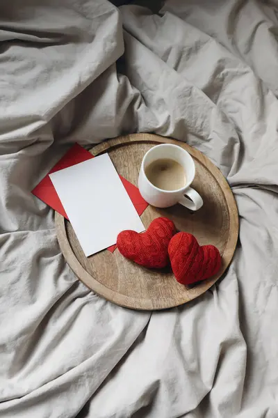 Valentines day, 14th Februray concept. Breakfast in bed. Cup of coffee and red hearts. Bedroom composition. blank greeting card, invitation mockup. Wedding, love concept, flat lay, top view, vertical.