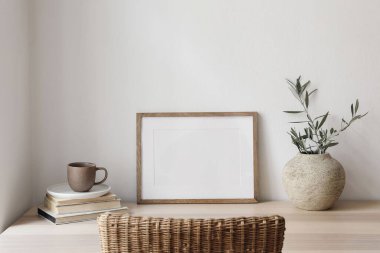 Boş yatay çerçeve modeli. Tahta masa, içinde kahve olan masa, bulanık rattan sandalye. İçinde zeytin dalı olan vazolar, eski kitaplar. Akdeniz iç mimarisi, ev, beyaz duvar arka planı.