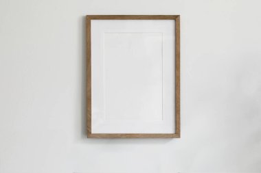 Beyaz duvarın ortasında asılı tek bir resim modeli afişi. Portre büyük 50x70, 20x28, a3, a4. Boş ahşap çerçeve modeli. Temiz, modern, minimal tasarım. İç dekorasyon, metin veya ürünü göster