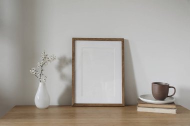 Dikey ahşap çerçeve, poster modeli. Bahar, Paskalya kompozisyonu. Asya iç mimarisi, ev ofisi hala hayat dolu. Sanatsal gösteri. Cam vazoda kiraz ağacı dalları açıyor. Tahta masa..