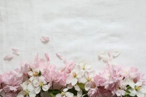 春の花の配置 白いリンゴの木の花 ぼやけた白いリネンテーブルクロスの背景にピンクの桜の木の境界を祝う Webバナー ポストカードのデザイン要素 — ストック写真