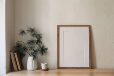 Noel kahvaltısı hala hayattadır. Minimum kış sanatsal kompozisyonu. Dikey olarak boş, ahşap çerçeve modeli, mantar tepside bir fincan kahve, masa. Çam ağacı dalları Modern beyaz vazo, eski kitaplar