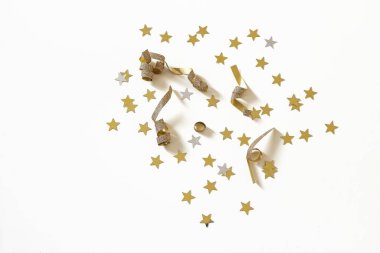 Altın metalik yıldız şekilli konfeti, beyaz masa arkasında izole edilmiş süs eşyası. Noel bayrağı. Kış parlak dekoratif düz yatak deseni. Üst Manzara. Doğum günü, yıldönümü yeni yıl kutlaması