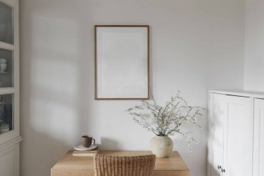 Bahar iç kısımları hala hayat. Bir fincan kahve, eski kitaplarda çay. Beyaz çiçek açan erik ağacı dalları bambu masadaki seramik vazoda dikey ahşap resim çerçevesi duvarda asılı poster modeli.