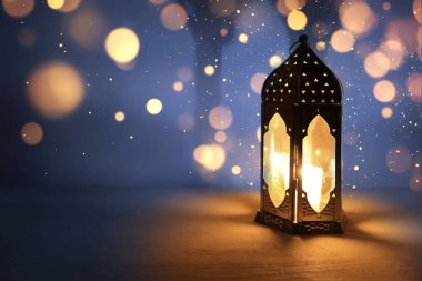 Ornamental dark Moroccan, Arabic lantern on table burning at night. Glittering bokeh lights. Greeting card for Muslim community holy month Ramadan Kareem, Eid Mubarak, festive background. clipart