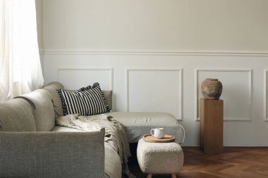 Zarif oturma odası dekoru. Modern İskandinav iç tasarımı. Bir fincan çay, tepside kahve, tabure. Gri kanepe, tahta kaide. Dokulu vazo. Güzel klasik duvar kalıpları. Boş kopyalama alanı.