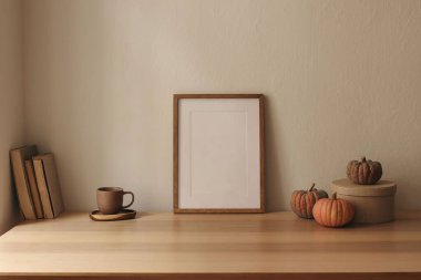 Tahta poster, çerçeve modeli. İskandinav oturma odası iç mekan, ev ofisi. Balkabakları, depolama kutusu, masada bir fincan kahve, masa. Sonbahar Şükran Günü ev dekorasyonu, bej duvar arka planı.