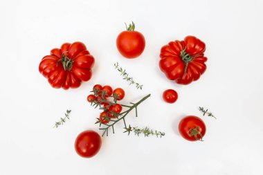 Çeşitli taze aile yadigarı, öküz kalbi, kiraz domatesleri. Düzenlenmiş kırmızı sebze çeşitleri, beyaz arka planda izole edilmiş kekik otları. Organik gıda, sağlıklı beslenme, hasat. Bahçe dairesi, üst görünüm