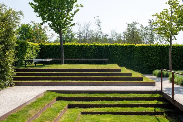 在园林里放松的座位 绿草台阶的简约景观设计 免版税图库照片