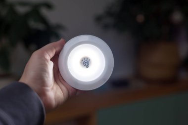 Pürüzsüz Arkaplanlar Arasında Küçük Aydınlık Bir Odada El Tutma Işığı. Modern ışıklandırma çözümlerinin günlük durumlarda yenilik ve taşınabilirliği. Karartma konsepti