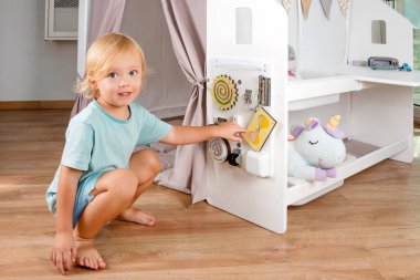 Yürümeye başlayan bir çocuk, neşeli bej aksanlı, neşeli hayal gücü ve güvenli ve rahat bir ortamda eğlenceli yaratıcılık içeren canlı bir oyun evini keşfeder.