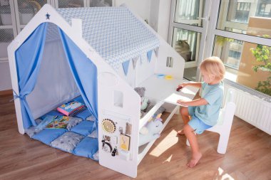 Yürümeye başlayan bir çocuk, neşeli mavi aksanlı, neşeli hayal gücü ve güvenli ve rahat bir ortamda eğlenceli yaratıcılığı olan canlı bir oyun evini keşfeder.