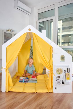 Küçük bir çocuk, güvenli ve rahat bir ortamda neşeli sarı aksanlı, neşeli hayal gücü ve eğlenceli yaratıcılığı olan canlı bir oyun evini keşfediyor.