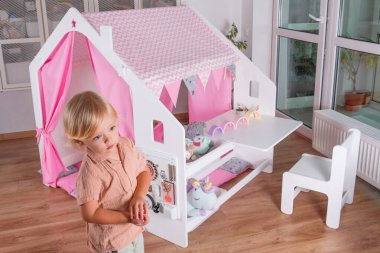 Yürümeye başlayan bir çocuk, güvenli ve rahat bir ortamda neşeli pembe aksanlı, eğlenceli hayal gücü ve eğlenceli yaratıcılığı olan canlı bir oyun evini keşfeder.