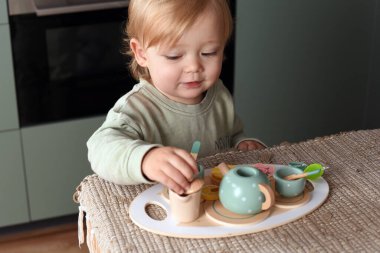 Yaratıcı oyun zamanı renkli bir oyuncak çay takımıyla oynayan küçük bir çocuk. Tahta oyuncaklar, Montessori, mutlu çocukluk..