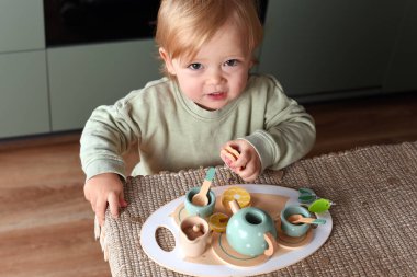 Yaratıcı oyun zamanı renkli bir oyuncak çay takımıyla oynayan küçük bir çocuk. Tahta oyuncaklar, Montessori, mutlu çocukluk..