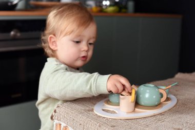 Yaratıcı oyun zamanı renkli bir oyuncak çay takımıyla oynayan küçük bir çocuk. Tahta oyuncaklar, Montessori, mutlu çocukluk..