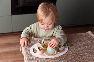 Yaratıcı oyun zamanı renkli bir oyuncak çay takımıyla oynayan küçük bir çocuk. Tahta oyuncaklar, Montessori, mutlu çocukluk..