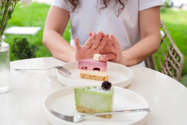 Açık havada Beyaz Tabaklar Üzerine Renkli Pastalar Üzerine Hareketli Kadın Hareketi. Şekere, diyete, perhize, diyete, kilo vermeye hayır. Pasta yok, kadın diyette.