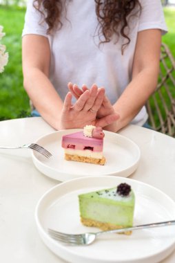Açık havada Beyaz Tabaklar Üzerine Renkli Pastalar Üzerine Hareketli Kadın Hareketi. Şekere, diyete, perhize, diyete, kilo vermeye hayır. Pasta yok, kadın diyette.
