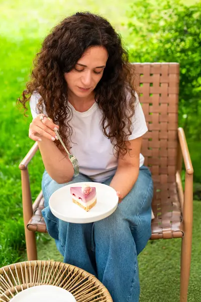 İki tabak tatlısıyla açık bir masada oturan bir kadın, huzurlu yeşil bir bahçede manzaranın ve sakin çevrenin tadını çıkarıyor. diyet konsepti, perhiz, diyet, kilo verme, diyet yapan kadın.