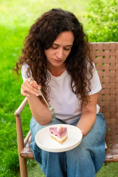 İki tabak tatlısıyla açık bir masada oturan bir kadın, huzurlu yeşil bir bahçede manzaranın ve sakin çevrenin tadını çıkarıyor. diyet konsepti, perhiz, diyet, kilo verme, diyet yapan kadın.