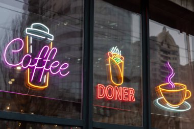 İçinde kahve, kebap ve cam vitrinde sergilenen bardak sembolleri olan neon lambaları. Bu parlak işaretler içecekleri ve yiyecekleri teşvik eder, müşteriler için canlı ve misafirperver bir atmosfer yaratır.