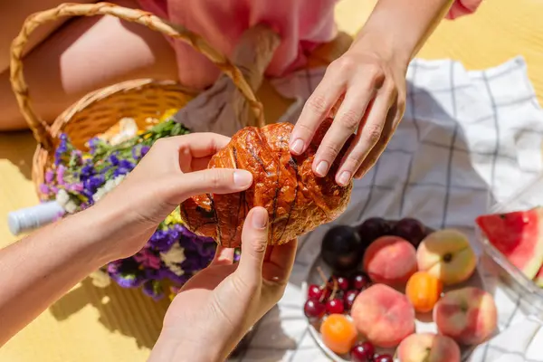 Rahat bir piknik ortamında iki kişi bir parça ekmeği paylaşıyor. Bu bir birliktelik, topluluk ve basit zevkleri yakalar. Boş zaman, bağlantı, ya da hayatın anlarının kutlaması