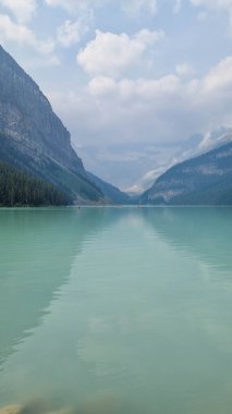 Louise Gölü, Alberta, Kanada - 8 Ağustos 2023: Louise Gölü 'nde turkuaz suda yüzen kırmızı kano. Güneşin doğuşunda Louise Gölü 'nde kano yapan çift.