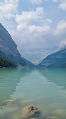 Louise Gölü, Alberta, Kanada - 8 Ağustos 2023: Louise Gölü 'nde turkuaz suda yüzen kırmızı kano. Güneşin doğuşunda Louise Gölü 'nde kano yapan çift.