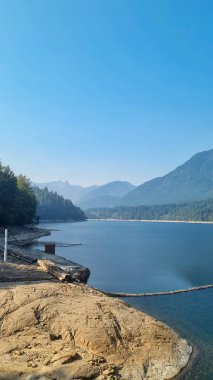 A scenic View of Cleveland Dam reservoir surrounded by mountains at sunset, North Vancouver, Canada. clipart