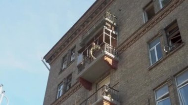 Bir adam balkonundan cam soyuyor. Rus İHA 'sının Kyiv' deki füze saldırısı sonucu hasar gören bir yerleşim yeri. 11 Ekim 2022