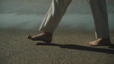 İnce kadın bacakları kumsalda yürüyor. Beyaz pantolon. Ağır çekim. Yüksek kaliteli FullHD görüntüler