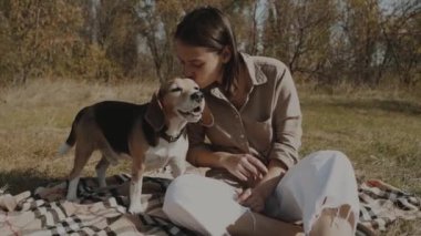 Kız parkta yürürken köpeğini öpüyor. Beagle. Köpek insanın en iyi dostudur, hayvanları sever. Yavaş çekim 120