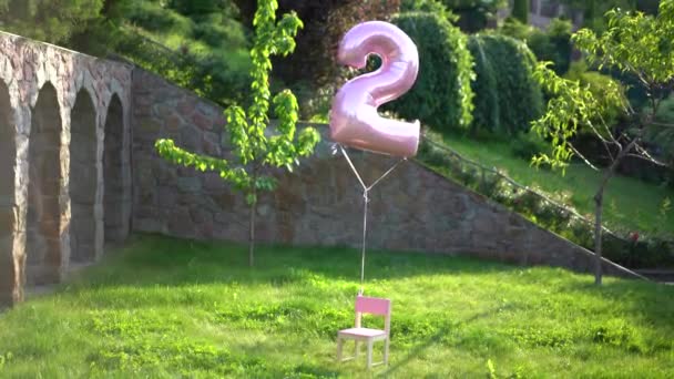 Розовый Шарик Номером Два Пролетает Над Маленьким Розовым Креслом Фоне — стоковое видео