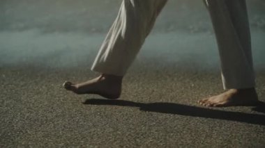 İnce kadın bacakları kumsalda yürüyor. Beyaz pantolon. Ağır çekim. Yüksek kaliteli FullHD görüntüler