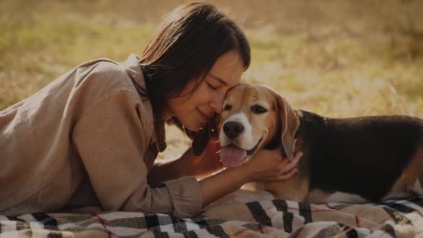 女の子は芝生の芝生の上に横たわって 彼女のビーグル犬と笑顔で抱き合っています コンセプト 犬は人間の親友 動物への愛です スローモーション120 キエフ2021 — ストック動画